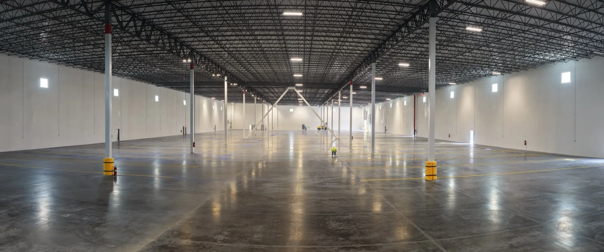 Wide panoramic of 1-800-PACK-RAT warehouse interior with yellow safety lines and steel bollards Tampa by Radiant Striping