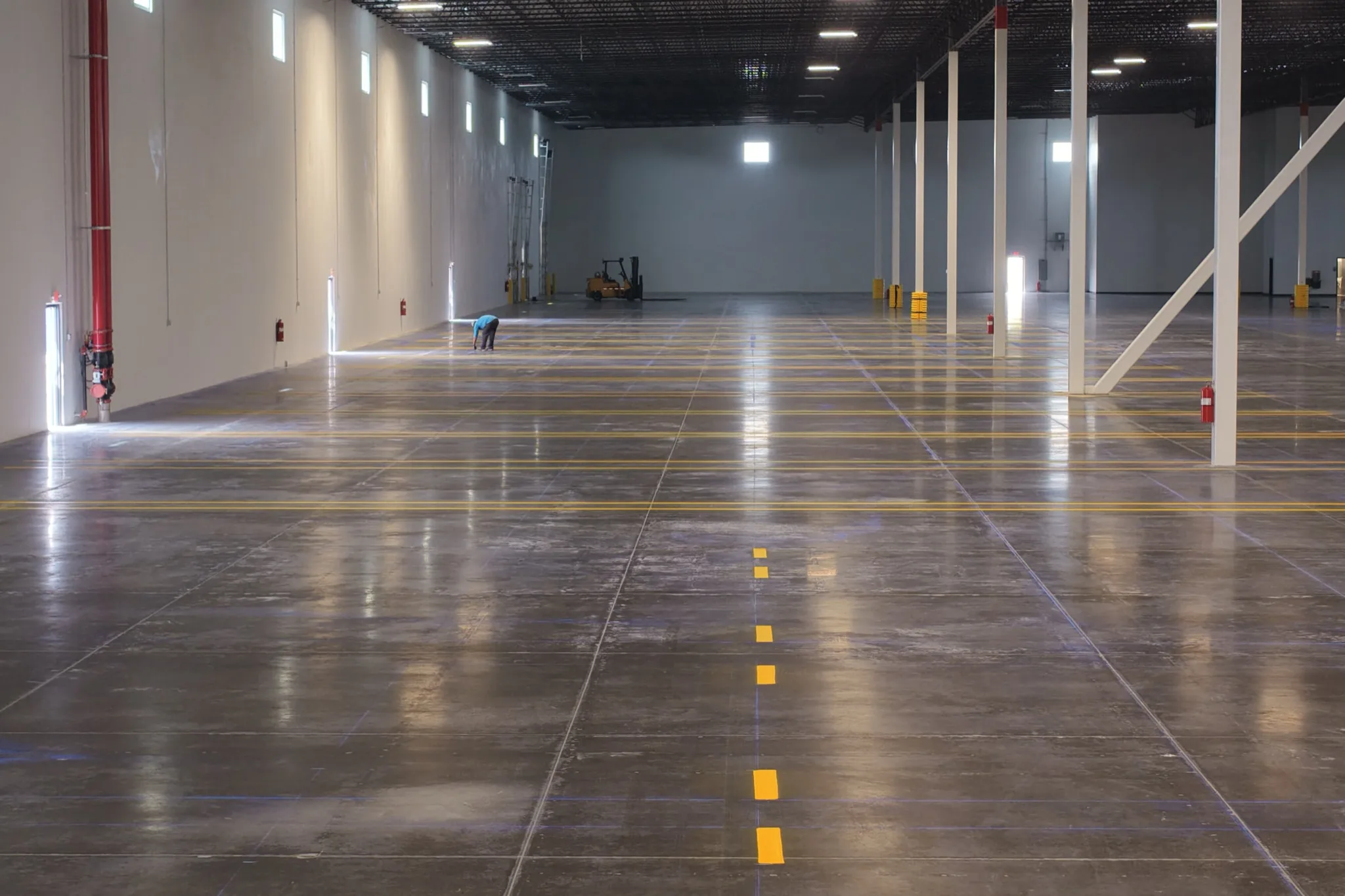 1-800-PACK-RAT warehouse interior with bright yellow forklift center lane line on polished concrete Tampa by Radiant Striping