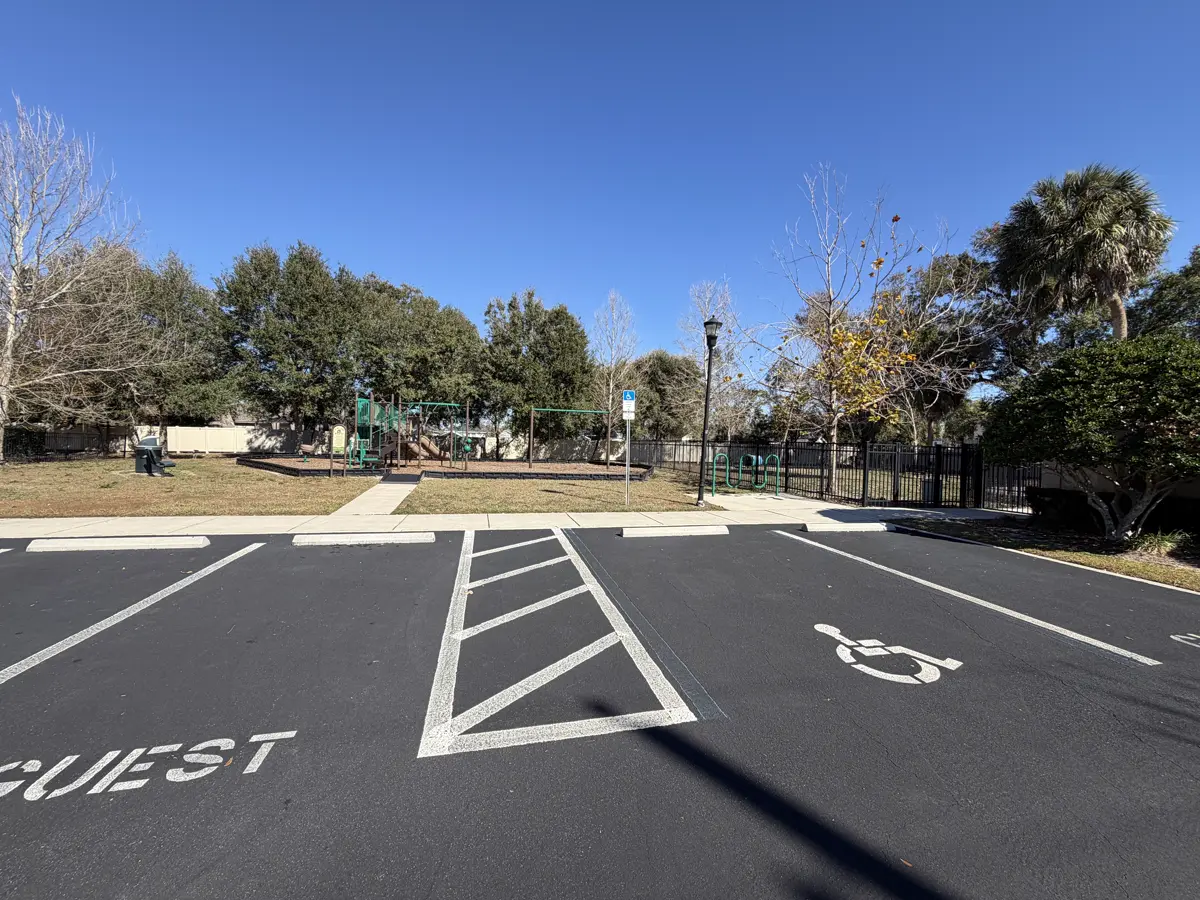 Guest parking stencil with ADA handicap symbol and white crosshatch access aisle on freshly sealcoated community parking lot - ADA compliant parking lot layout by Radiant Striping Tampa Florida
