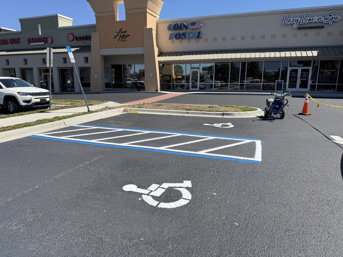 ADA compliant handicap parking spaces with wheelchair symbol stencil blue border markings and white crosshatch access aisle at commercial strip mall - ADA parking lot striping by Radiant Striping Tampa Florida