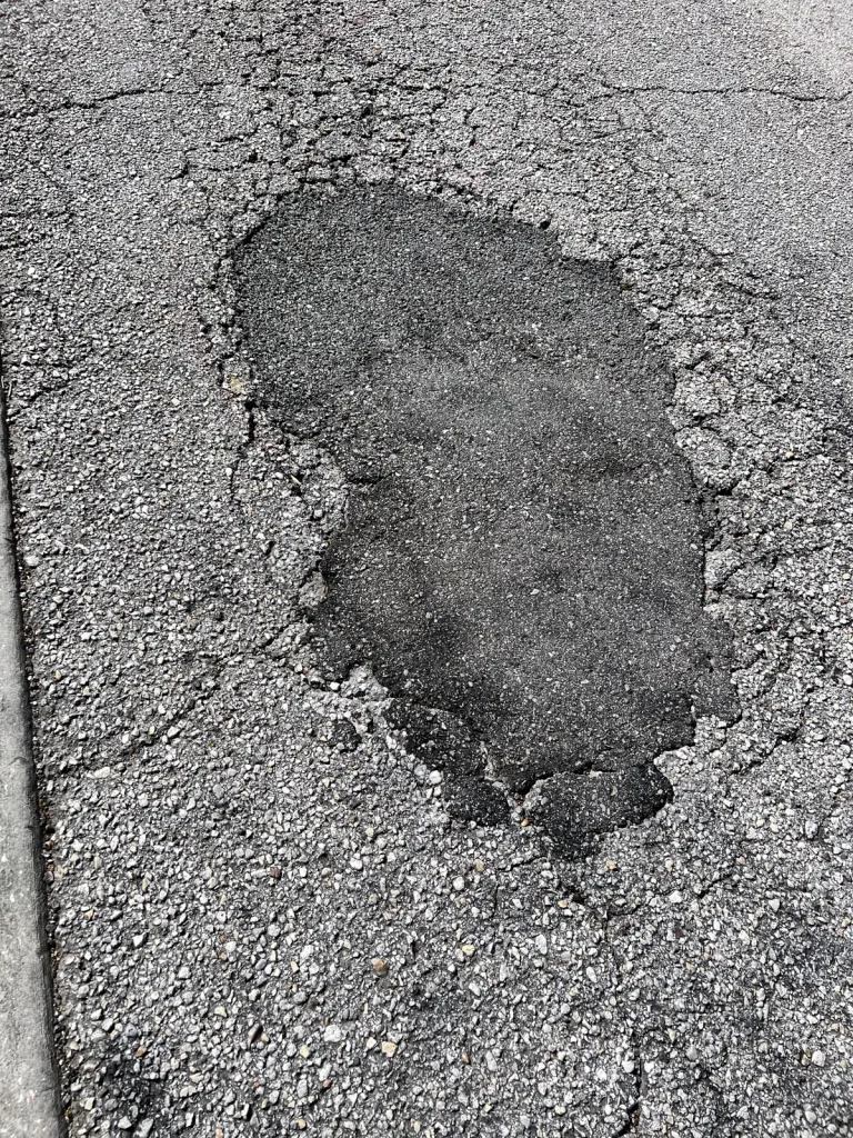 Close-up of freshly patched pothole showing clean asphalt repair work by Radiant Striping Tampa