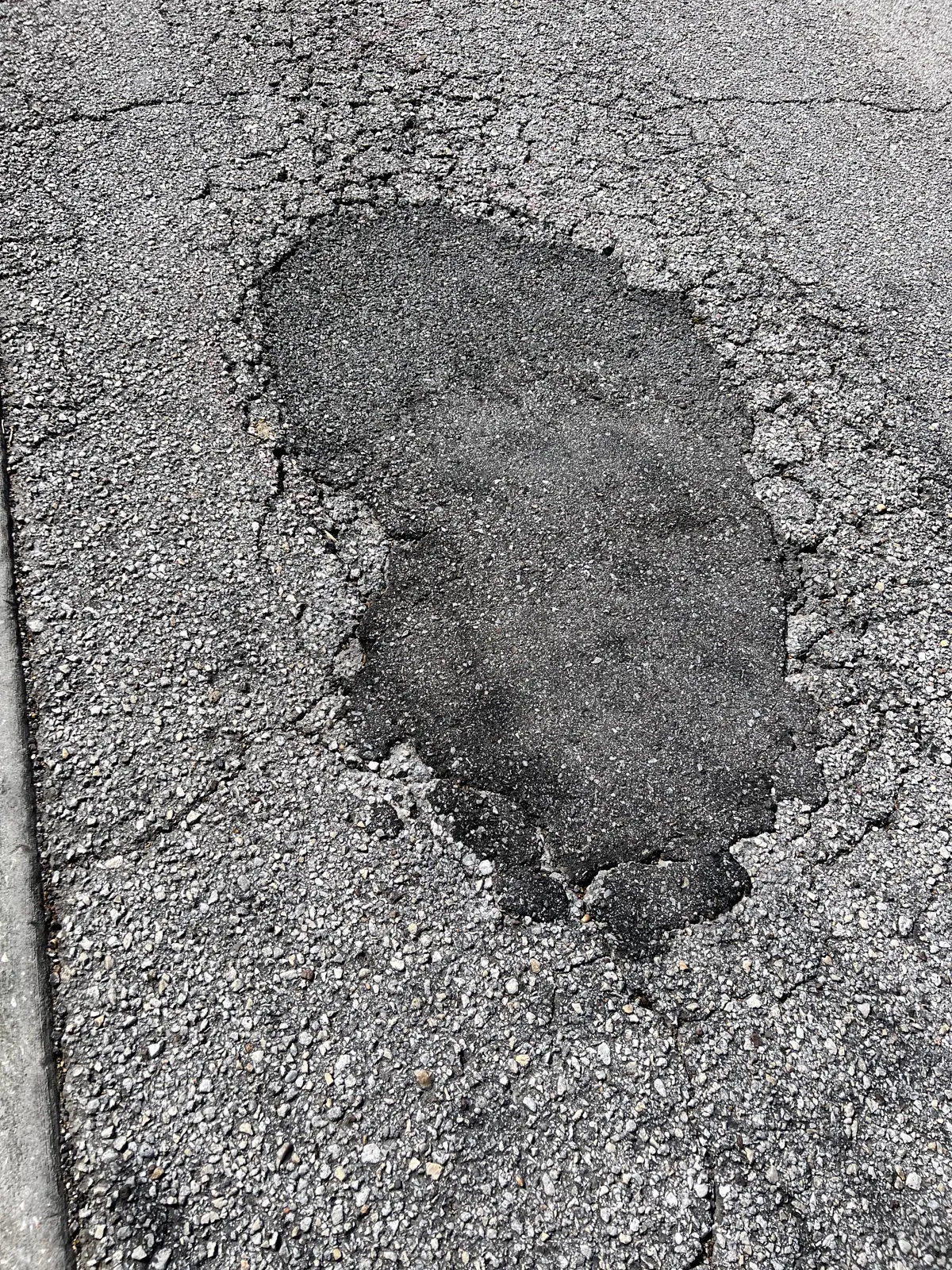 Close-up of freshly patched pothole showing clean asphalt repair work by Radiant Striping Tampa