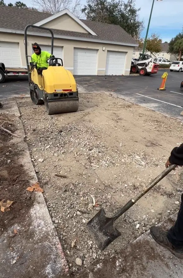 Radiant Striping crew compacting asphalt base with vibratory roller during commercial parking lot repair in Tampa