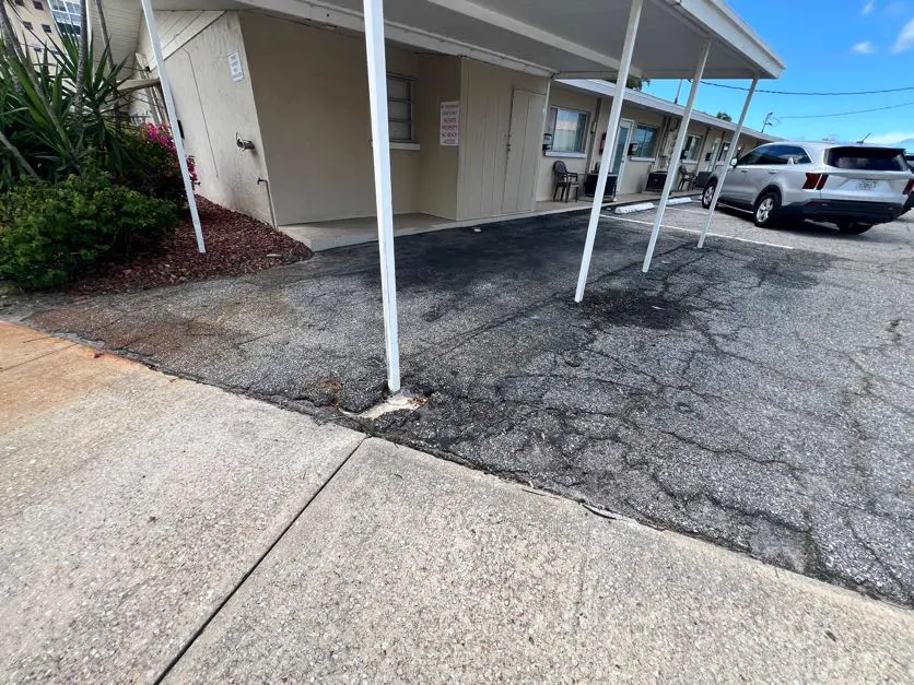 Cracked and deteriorated motel parking lot with widespread surface damage before commercial asphalt repair by Radiant Striping Tampa