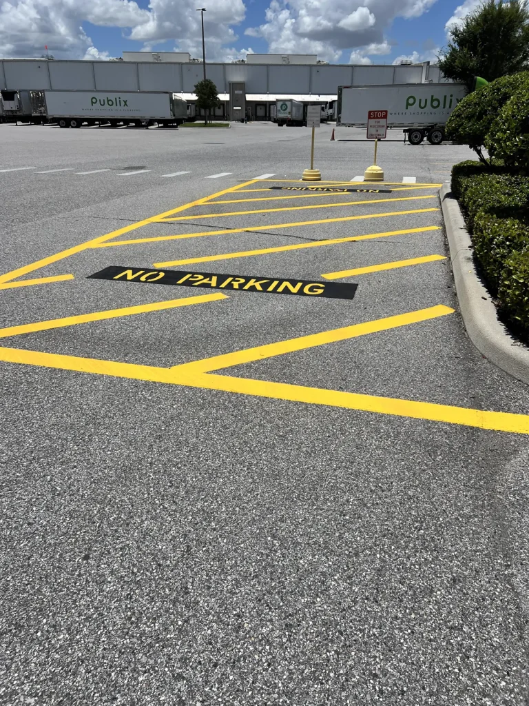 Fresh yellow no parking fire lane stencil and chevron hatching painted on commercial parking lot at Publix plaza in Tampa Florida by Radiant Striping showing code-compliant fire lane markings with bright yellow lines and clear no parking zone stenciling