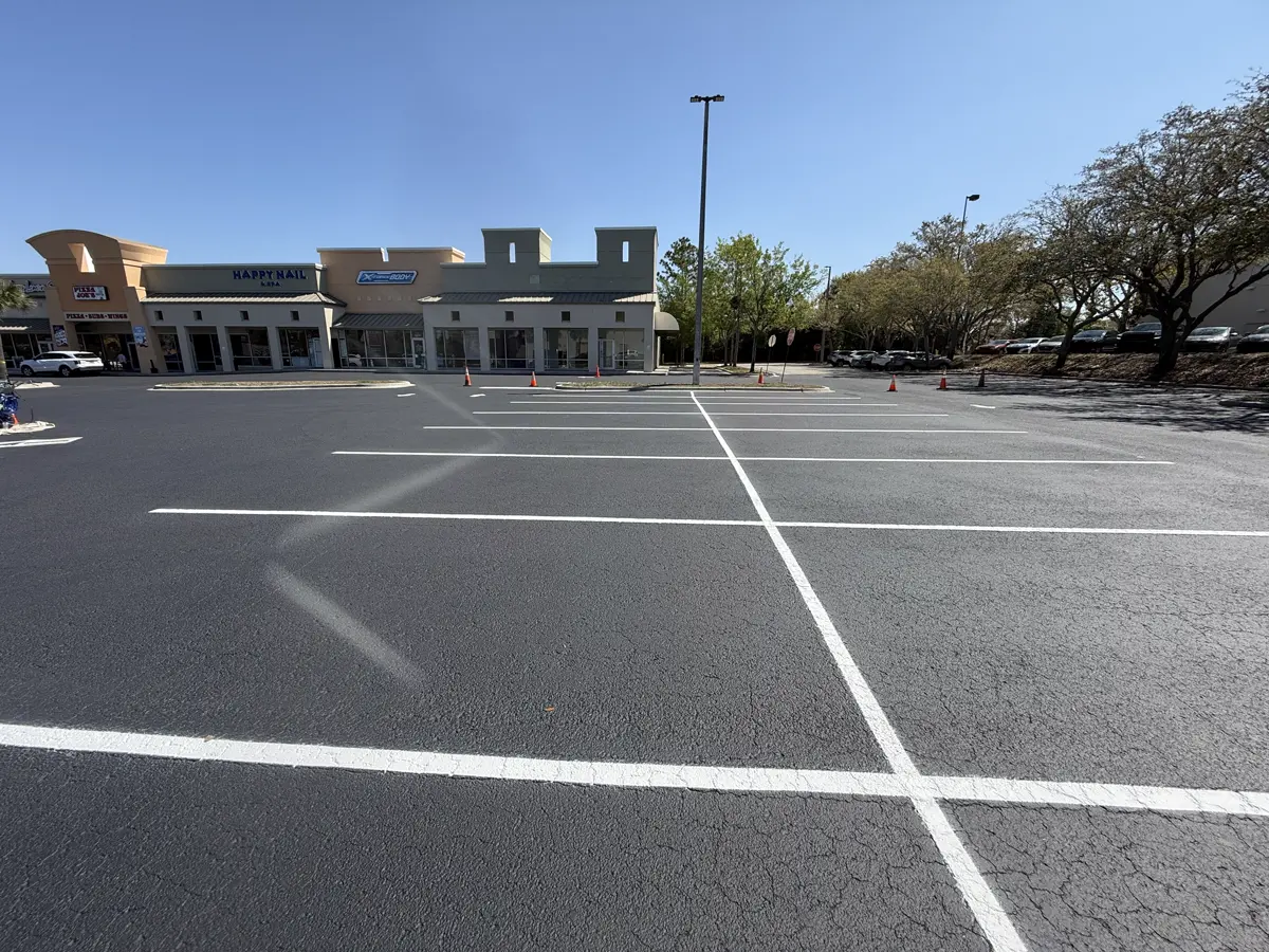 Sealcoated shopping center parking lot wide view storefronts Palm Harbor Florida by Radiant Striping