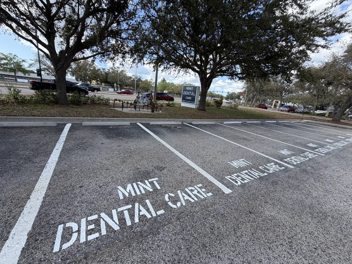 Custom reserved parking stencils reading Mint Dental Care painted in crisp white lettering across four consecutive stalls by Radiant Striping in Tampa Florida