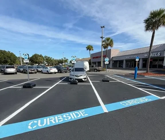 Curbside pickup stencils and fresh parking lot striping at a shopping plaza in Lakeland, Florida, completed by Radiant Striping