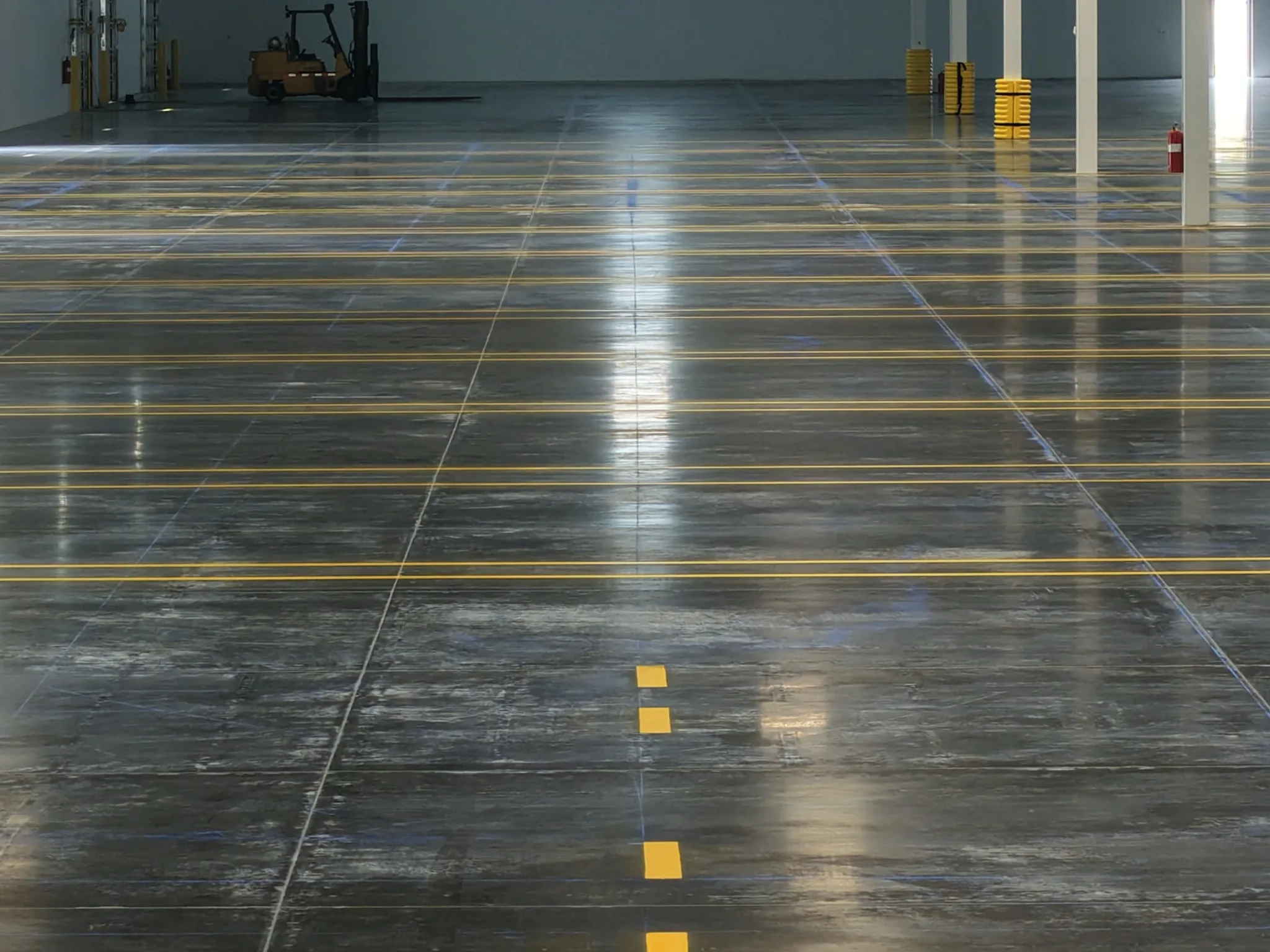 Completed yellow forklift lane lines on warehouse polished concrete floor 1-800-PACK-RAT Tampa by Radiant Striping