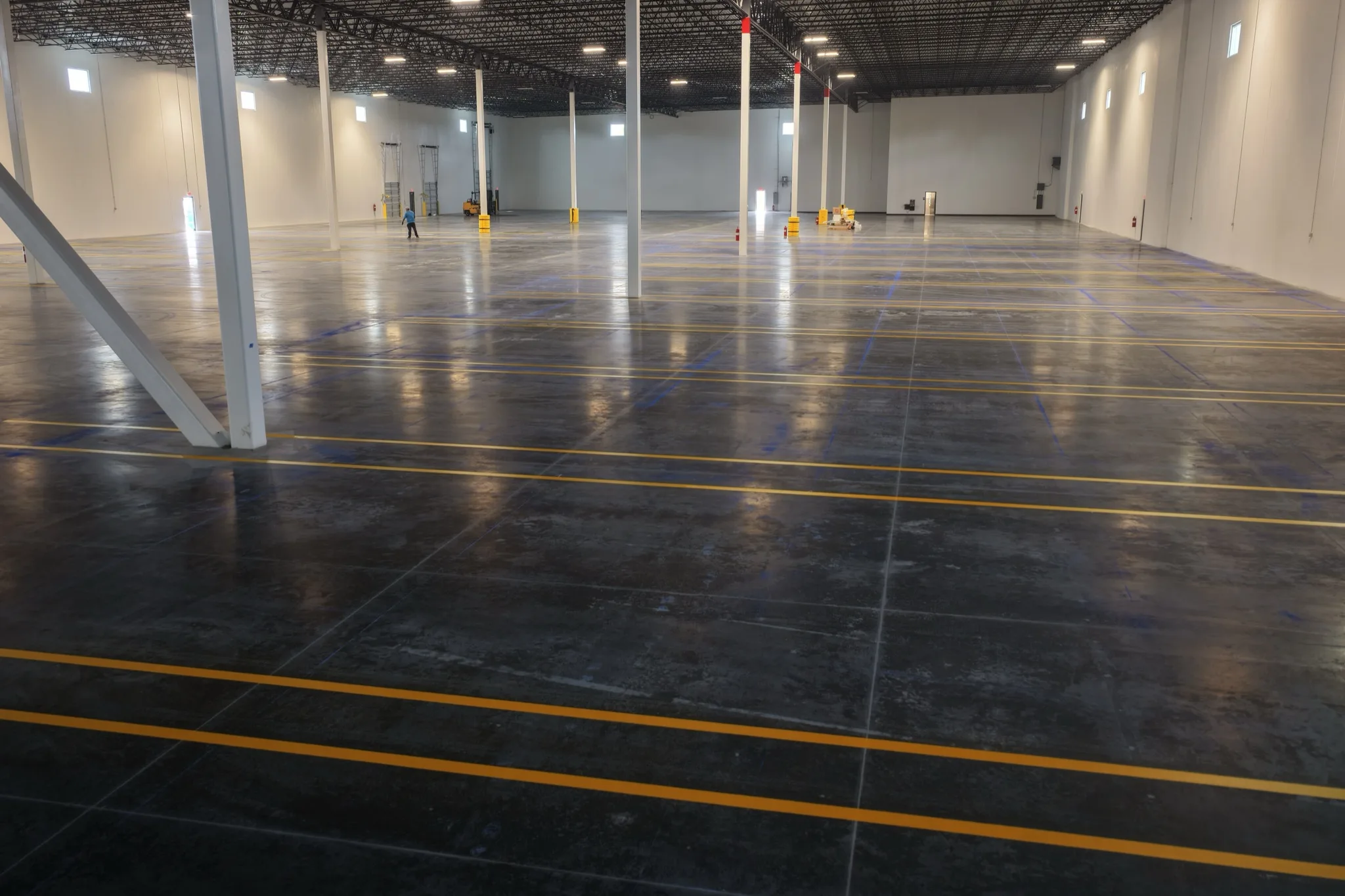Parallel yellow safety lines on polished concrete warehouse floor 1-800-PACK-RAT Tampa by Radiant Striping