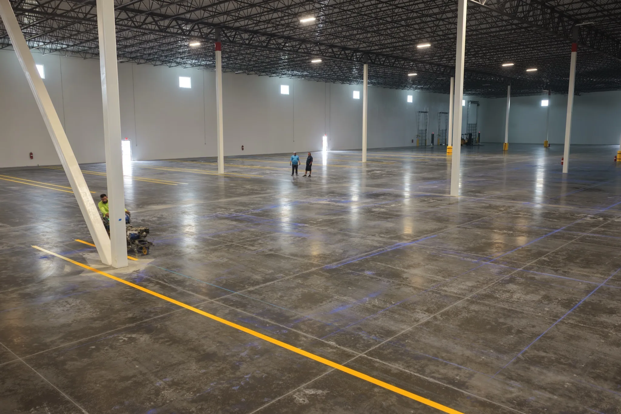 Radiant Striping crew applying yellow safety lines in 1-800-PACK-RAT warehouse Tampa