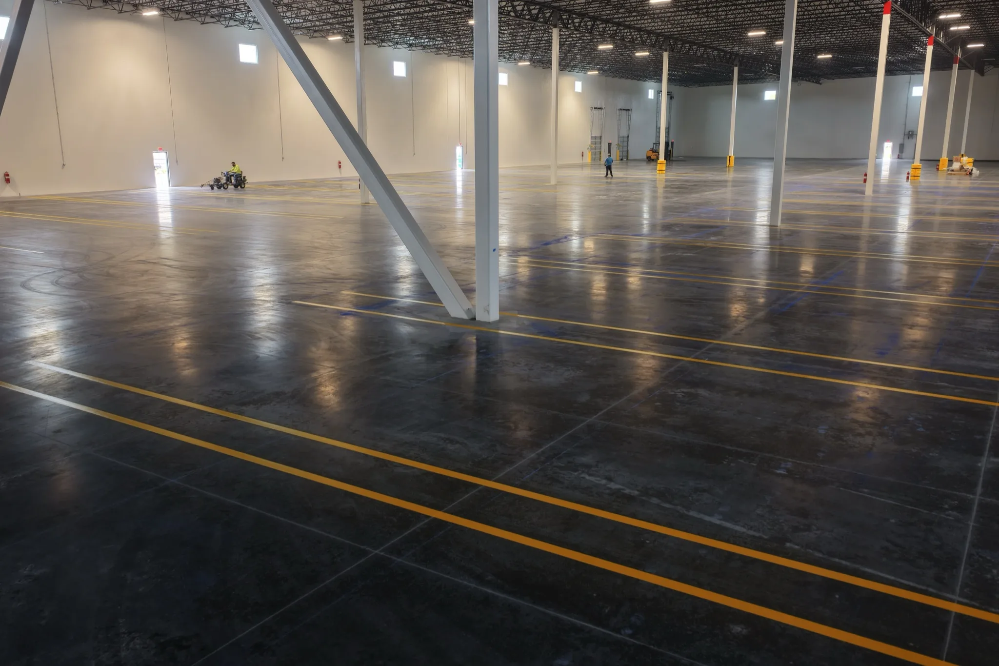 Wide angle of yellow warehouse safety lines with structural steel beam 1-800-PACK-RAT Tampa by Radiant Striping